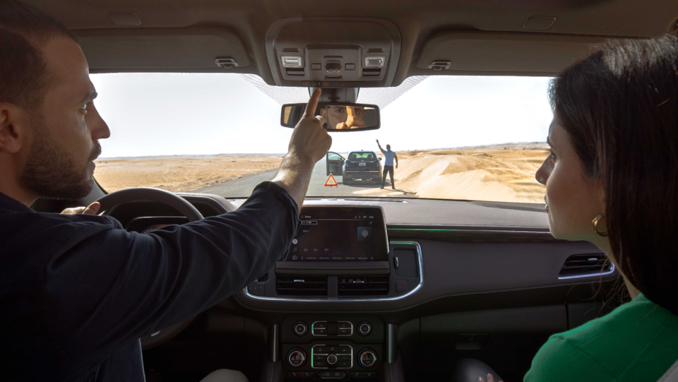 man and woman in car and man is pressing the OnStar button