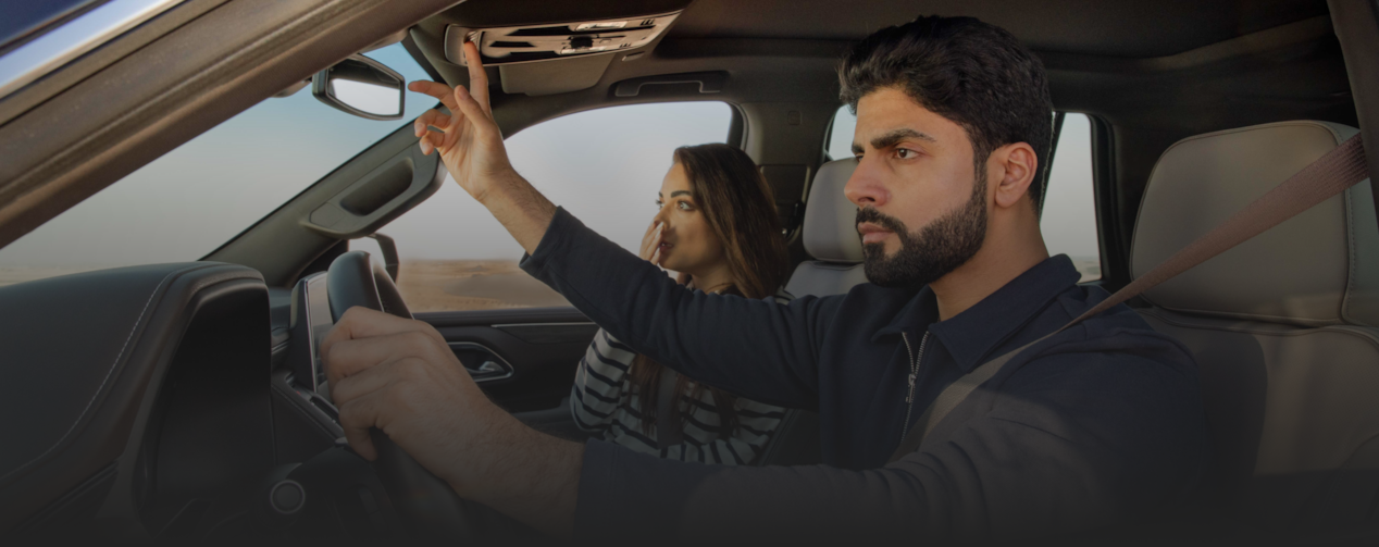 man and woman inside the car pressing the OnStar button