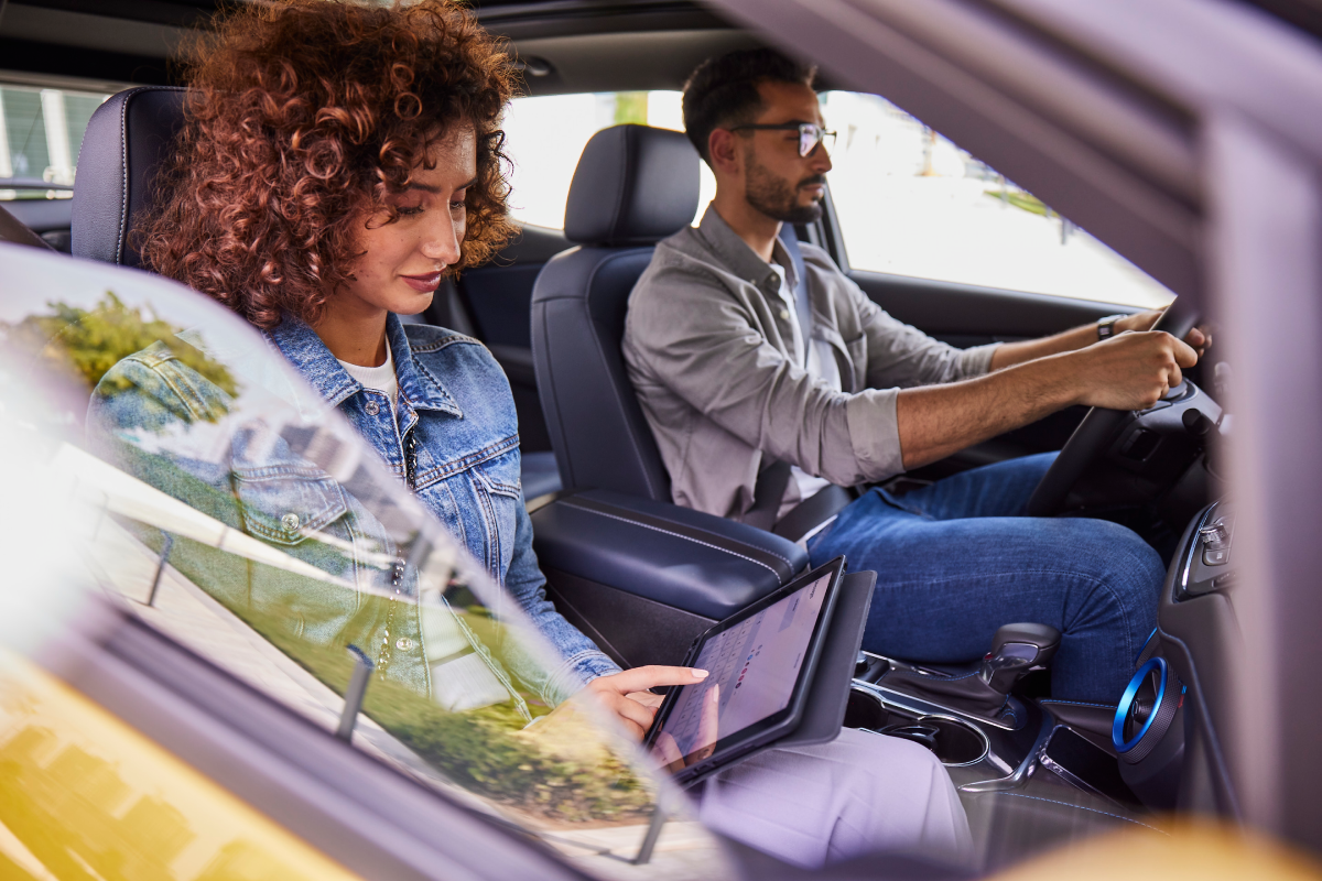 Woman looking at the tab and man driving beside her