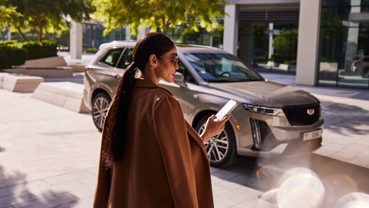 Woman holding a phone in front of a car